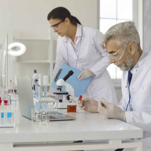 Senior male scientist doing experiments in laboratory by pipetting samples of cell culture medium.