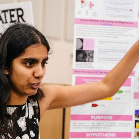 A science fair student explaining her project to a judge