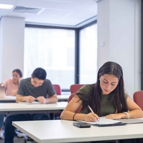A group of high school students sit at desks and take a test during class.