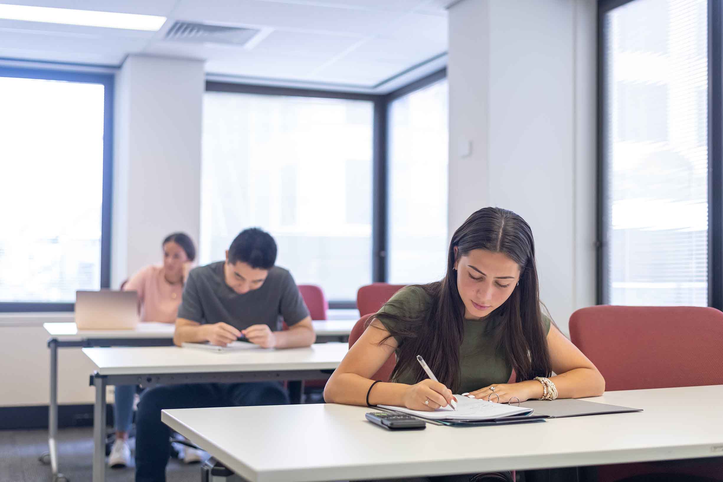 A group of high school students sit at desks and take a test during class.