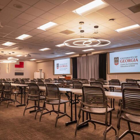 View inside of Conference room K/L with projection screens, tables and chairs lined up and ready.