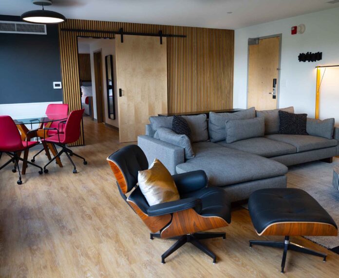 Alumni Queen Suite viewing the living area with couch, stripe coffee table, and lamps.