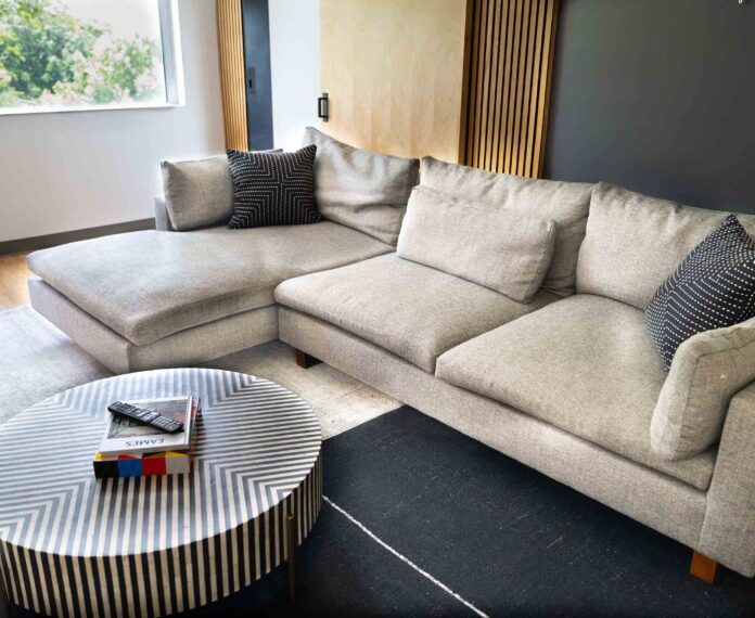 View of the Vice President's Queen suite with a tan couch and black and white dotted pillows and a black and white stripe coffee table with books and remote on top