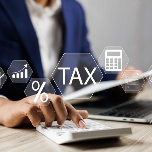 Businesman using calculator and laptop to complete Individual income tax return form online for tax payment.