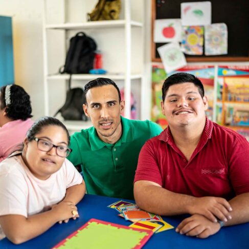 Portrait of mid adult teacher with developmental disability with his students in an inclusive classroom.