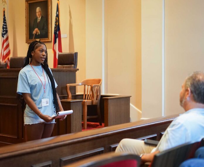 Student standing a courtroom speaking to a jury.