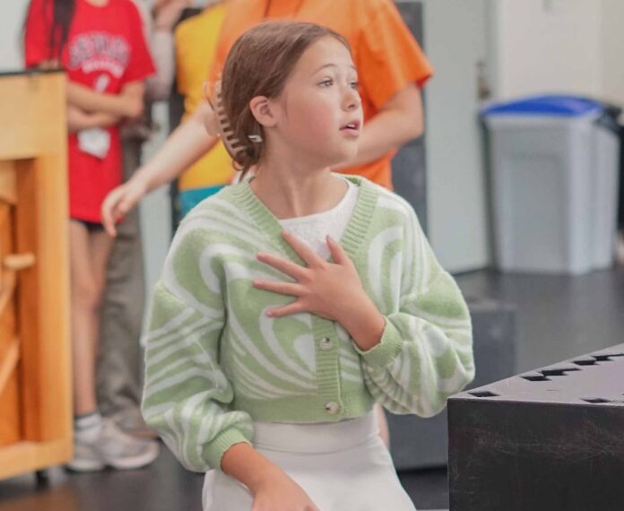 A young student acting out a scene in a classroom