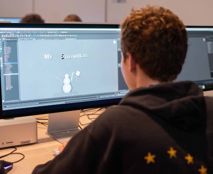Student looking at the computer screen with a drawing of a snowman in a classroom