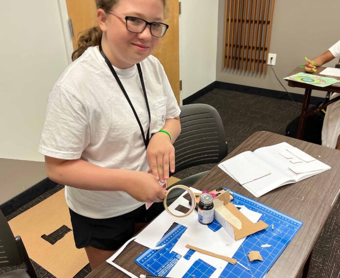 student building a structure on a table by following a diagram in a classroom