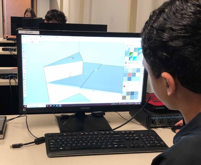 Student looking at building design on a computer screen in a classroom