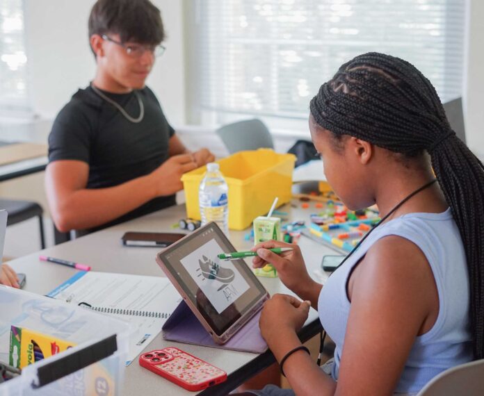 Two students using Lego's and a digital pad to learn about financial planning