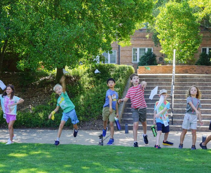 Group of students launching paper airplanes outside