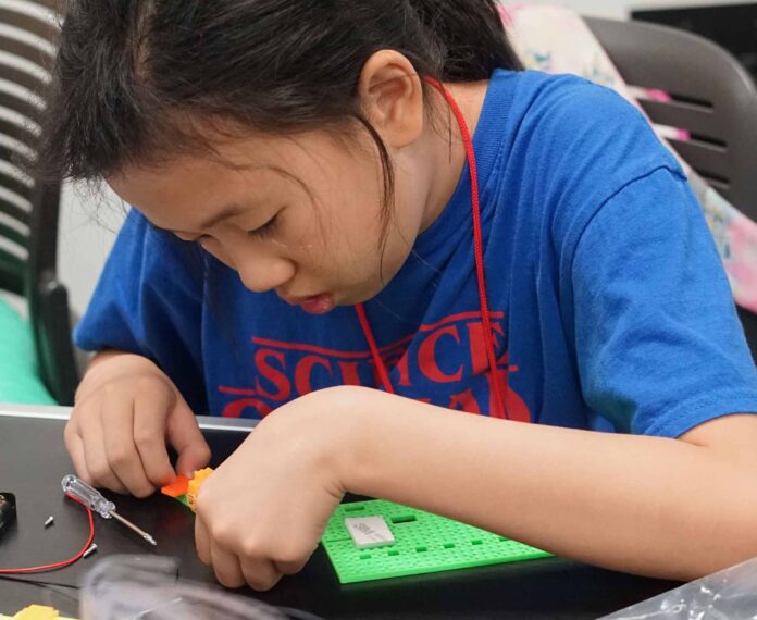 student putting a project together using a screwdriver and plastic pieces.