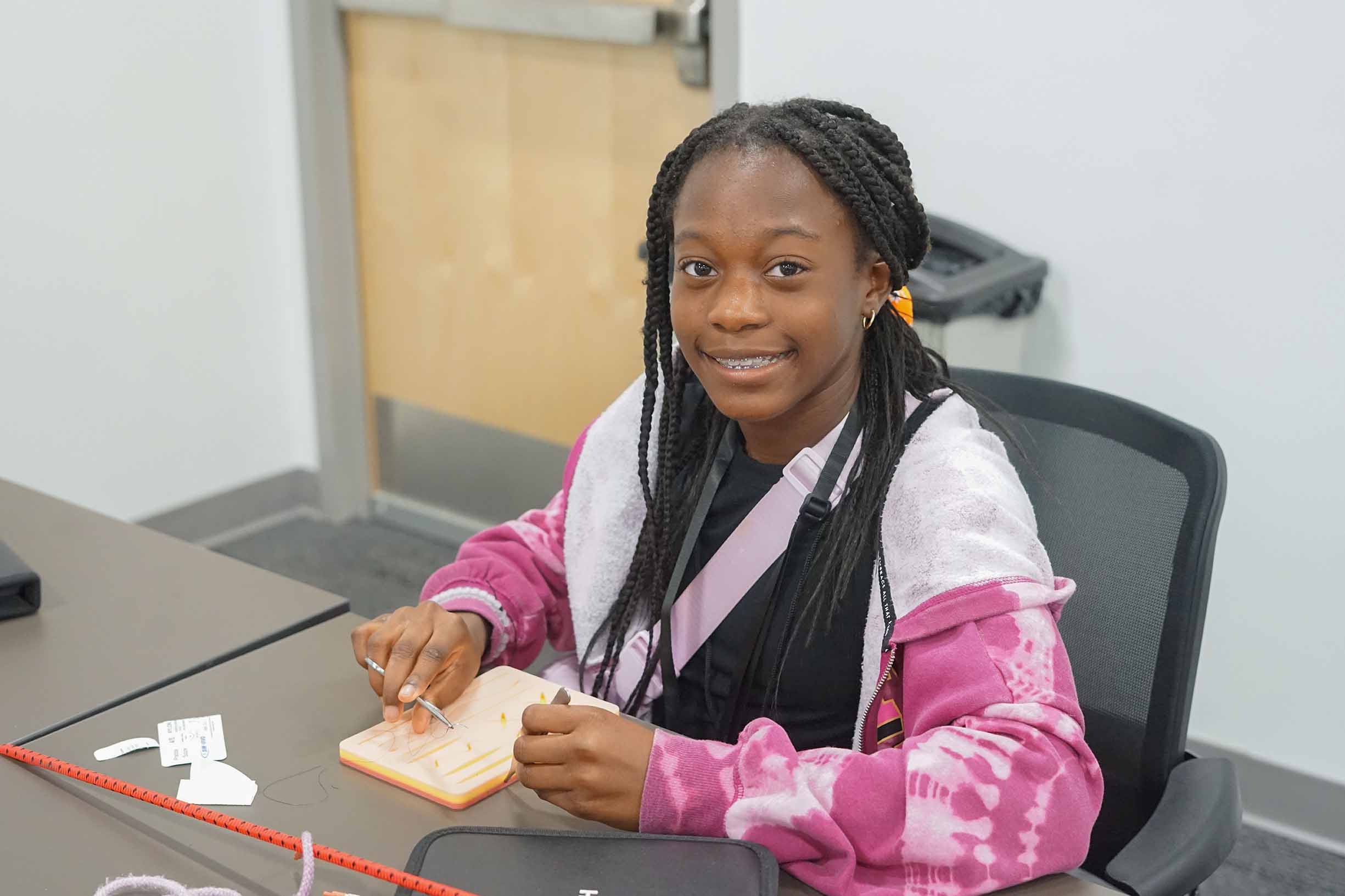 female student using a stitching kit sitting in a classroom