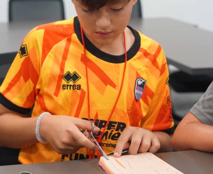 male student using a stitching kit sitting in a classroom