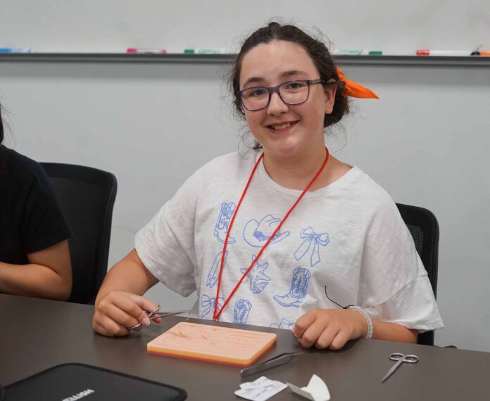 female student using a stitching kit sitting in a classroom