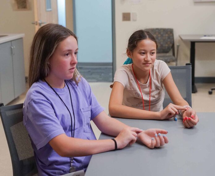 two students taking their pulse in a classroom