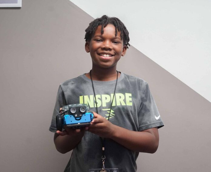 male student holding his robot he made in camp