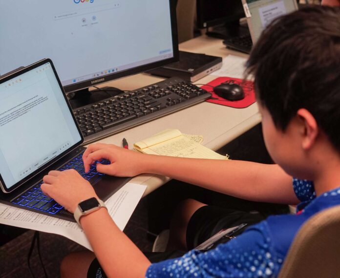 A view of a computer screen with some text that was typed by a student sitting at a desk in a classroom.