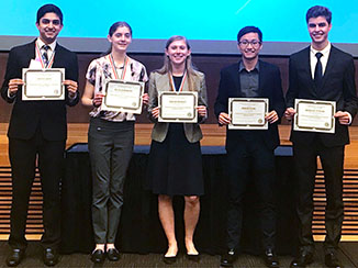 Five students who won awards standing on a stage.