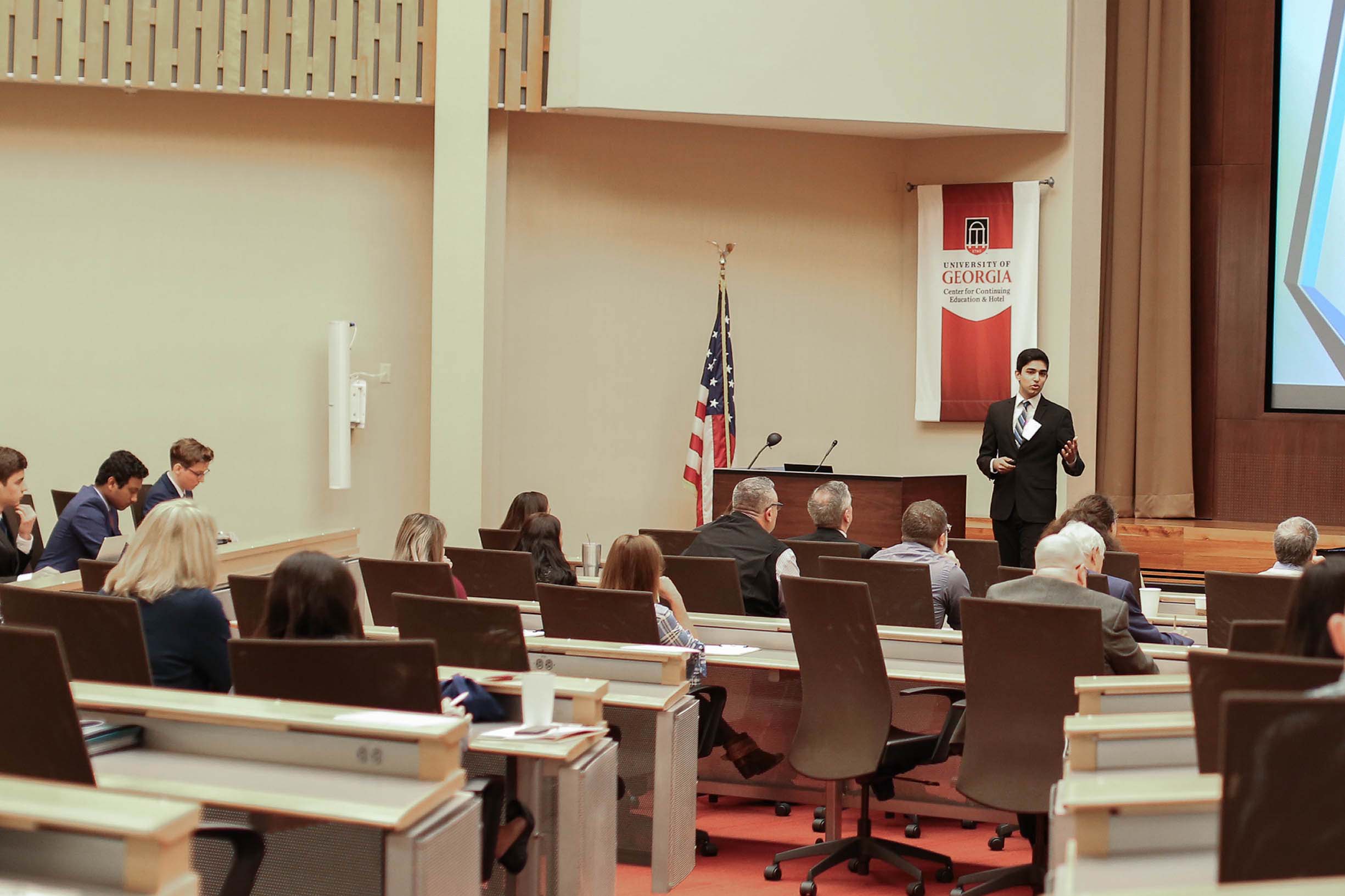 A student standing in front of a group in the Masters Conference room at the Georgia Center.