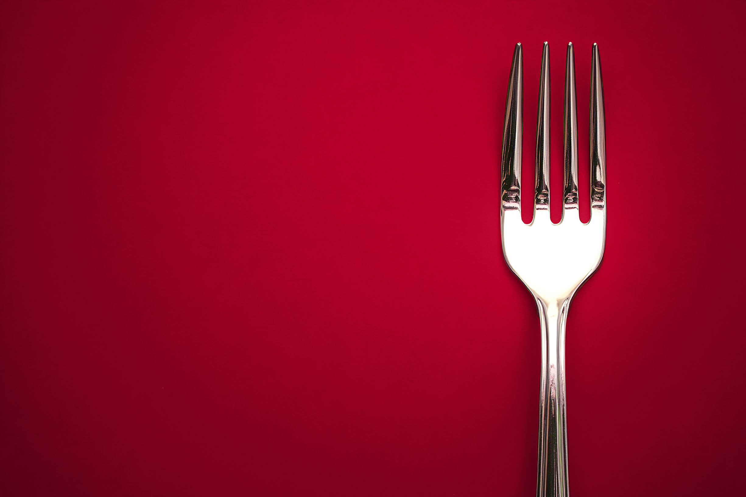Single fork displayed off center on a red background