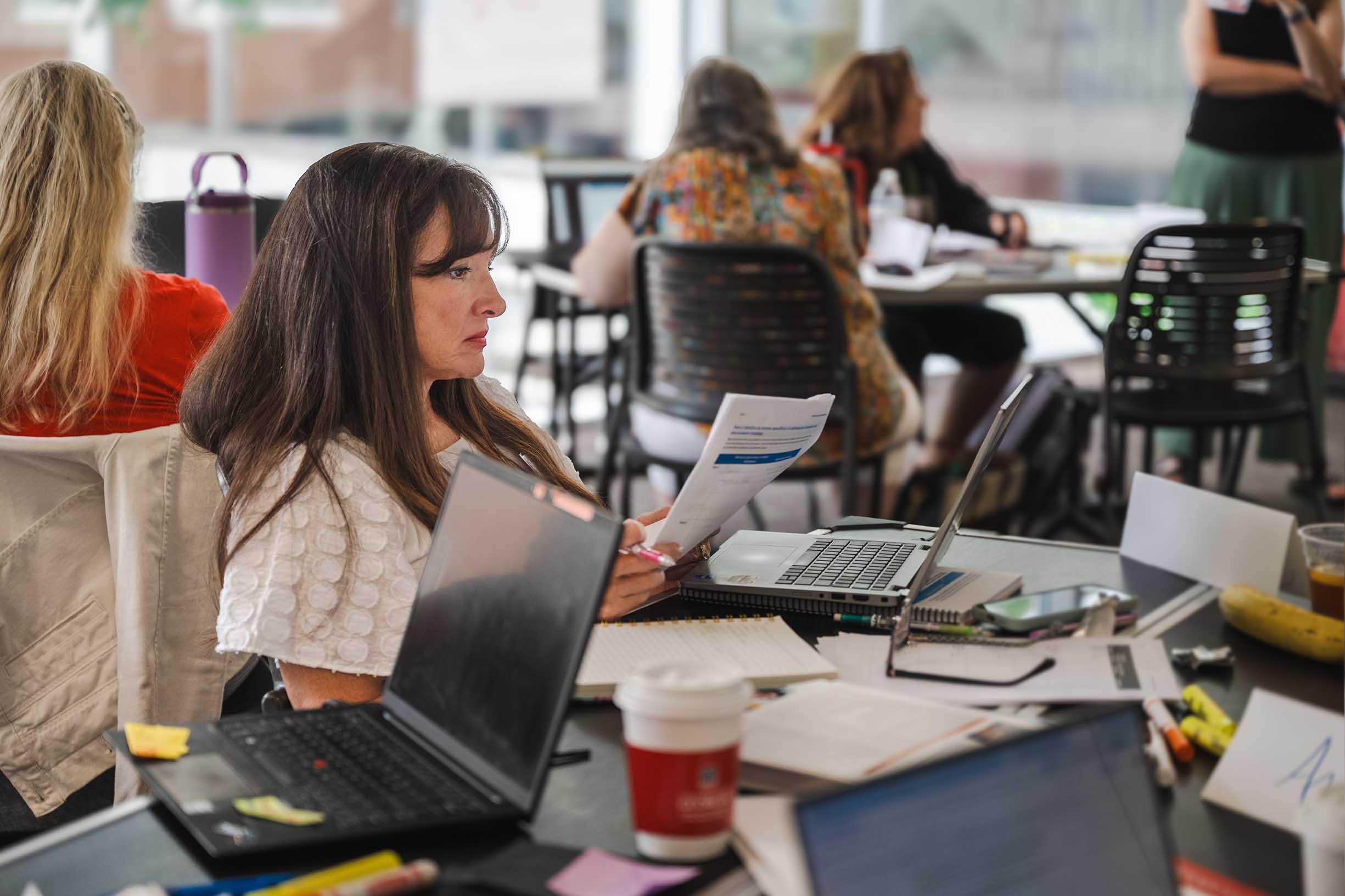 A woman reading her paper while sitting in front of a computer at the Georgia Center.